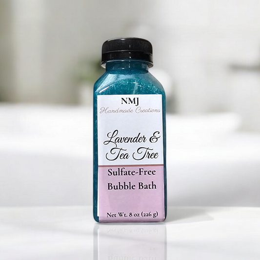 NMJ Handmade Creations sulfate-free bubble bath in 'Lavender & Tea Tree', displayed in a clear bottle with vibrant blue contents and a purple label, set against a minimalist white bathroom backdrop.