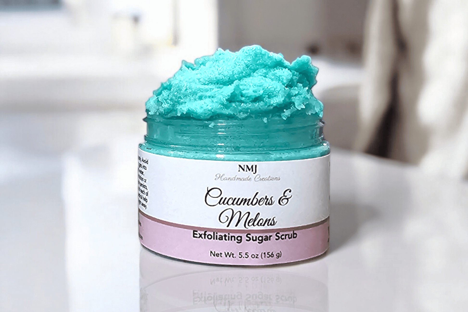 Exfoliating Sugar Scrub with Cucumbers & Melons, 5.5 oz jar, showcasing vibrant blue scrub texture, by NMJ, for radiant skin care.