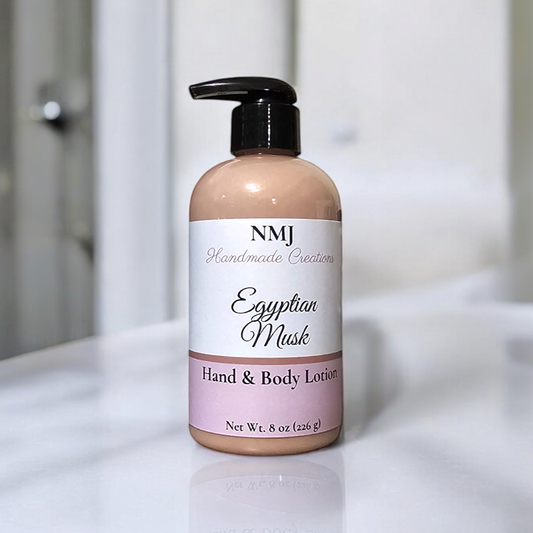 NMJ Handmade Creations' Egyptian Musk hand and body lotion, displayed in a clear bottle with a soft taupe label, is set against a clean, white bathroom backdrop