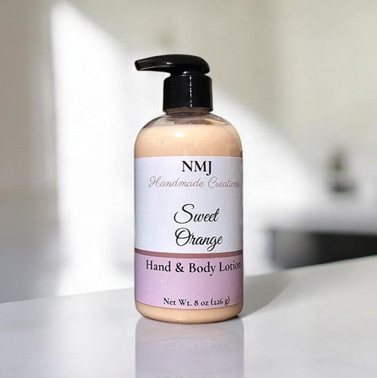 NMJ Handmade Creations' Sweet Orange hand and body lotion, showcased in a clear bottle with a peach label, rests elegantly against a minimalist white bathroom setting