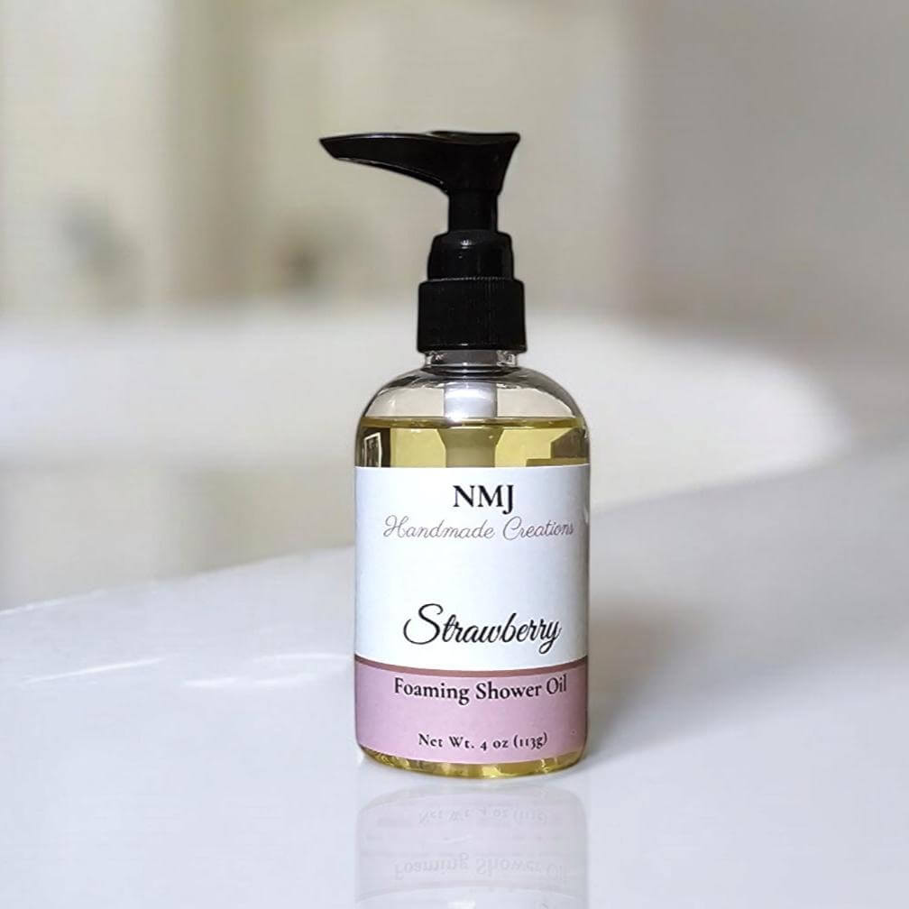 Foaming Shower Oil in 4 oz bottle with fresh strawberry scent by NMJ, displayed on a bath edge.