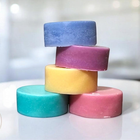 stack of conditioner bars in a cascade of colors, including teal, yellow, pink, purple, and light blue, each featuring a distinct texture. Arranged artistically on a bathroom counter, these bars provide an environmentally friendly hair care option